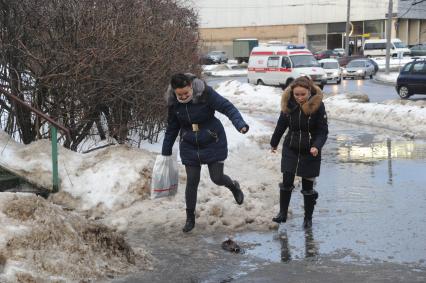 Москва.   Девушки обходят лужу  на тротуаре.