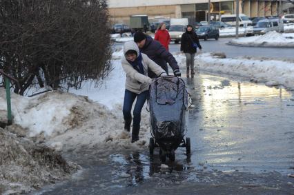 Москва.   Люди обходят лужу  на тротуаре.