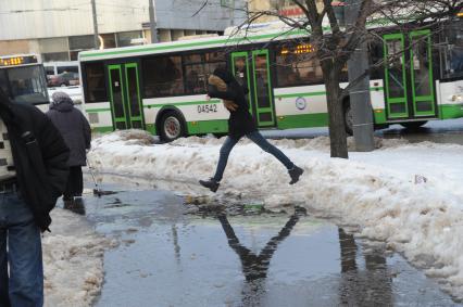 Москва.  Девушка обходит лужу  на тротуаре.