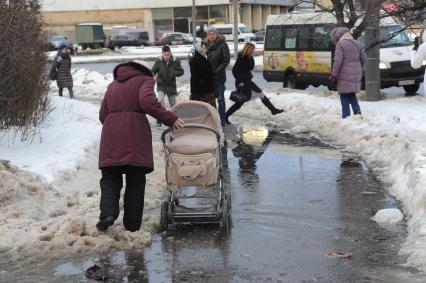 Москва.   Люди обходят лужу  на тротуаре.