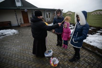 Украина. с.Александровка, Донецкая область. Отец Владимир окропляет святой водой людей рядом с церковью, стоящей на линии фронта.