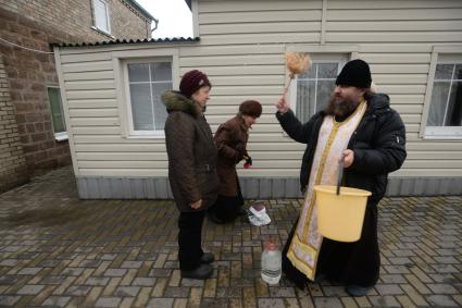 Украина. с.Александровка, Донецкая область. Отец Владимир окропляет святой водой женщин рядом с церковью, стоящей на линии фронта.