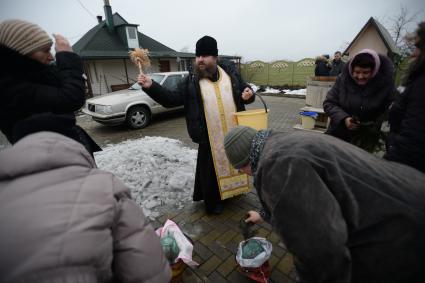 Украина. с.Александровка, Донецкая область. Отец Владимир окропляет святой водой женщин рядом с церковью, стоящей на линии фронта.