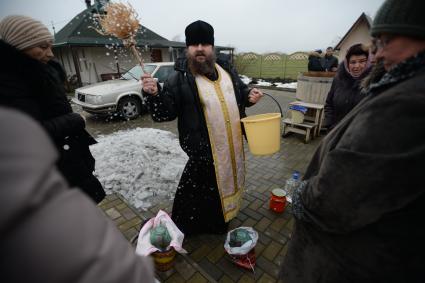 Украина. с.Александровка, Донецкая область. Отец Владимир окропляет святой водой женщин рядом с церковью, стоящей на линии фронта.