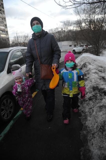 Москва. Женщина с детьми в медицинский масках во время прогулки.