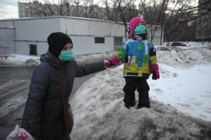 Москва. Женщина с ребенком в медицинских масках во время прогулки.