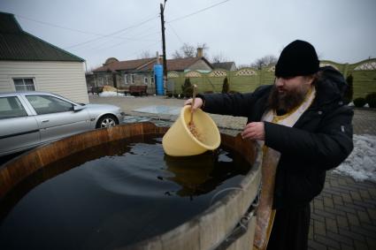 Украина. с.Александровка, Донецкая область. Отец Владимир набирает воду рядом с церковью, стоящей на линии фронта.