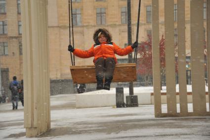 Москва.    Мальчик качается на качелях на Триумфальной площади.