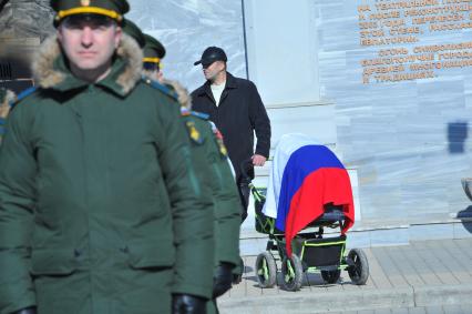 Евпатория. Мужчина с детской коляской и российским флагом на церемонии вручения Боевого знамени 40-му отдельному командно-измерительному комплексу войск воздушно-космической обороны на центральной площади.