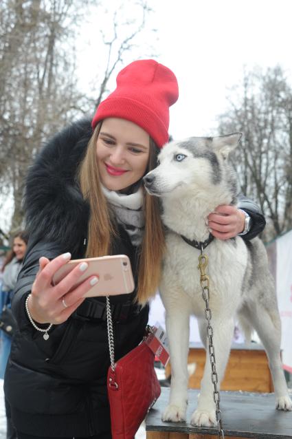 Москва.   Девушка делает селфи с хаски в парке Сокольники.