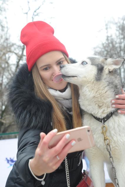 Москва.   Девушка делает селфи с хаски в парке Сокольники.