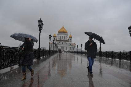 Москва.  Прохожие идут по  Патриаршему мосту  во время дождя.