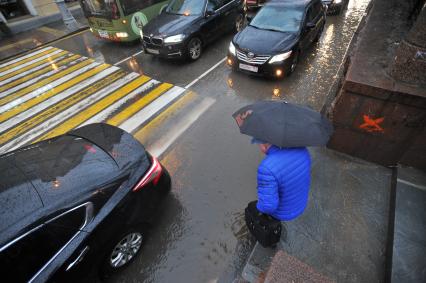 Москва. Мужчина пытается обойти лужу на пешеходном переходе  на Гоголевском бульваре.