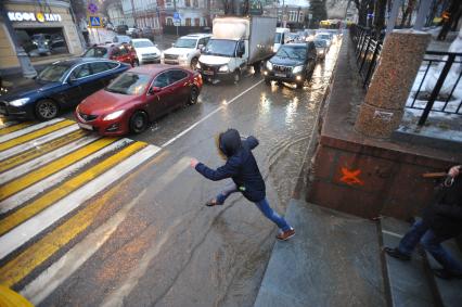 Москва.  Мальчик прыгает через лужу на пешеходном переходе  на Гоголевском бульваре.
