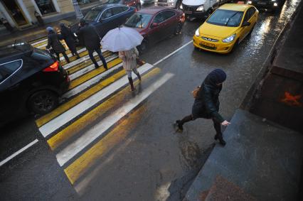 Москва.   Люди обходят лужу  на пешеходном переходе  на Гоголевском бульваре.