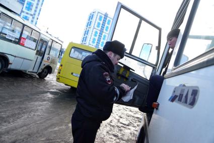 Екатеринбург. Сотрудник полиции проверяет документы у водителя маршрутного автобуса во время совместного рейда ГИБДД и Ространснадзора по выявлению нарушений ПДД и неисправных автобусов.