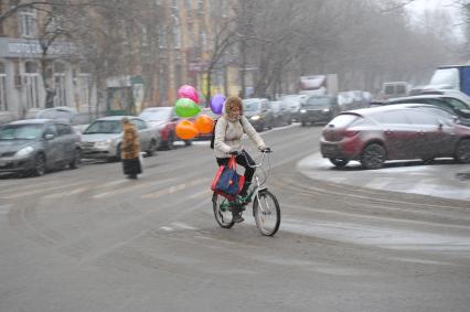 Москва.  Женщина едет на велосипеде по дороге.