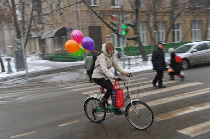 Москва.  Женщина едет на велосипеде по дороге.