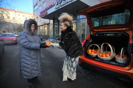 Москва. Писательница Лена Ленина угощает прохожих апельсинами возле редакции `Комсомольской правды`.