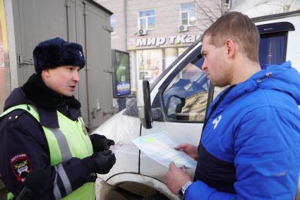 Екатеринбург. Сотрудник ДПС проверяет документы у водителя во время совместного рейда с судебными приставами по поиску должников.