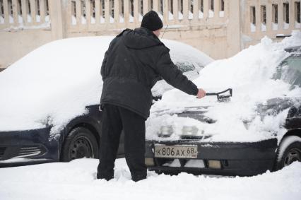 Москва.  Мужчина чистит свой автомобиль от снега на одной из улиц города.