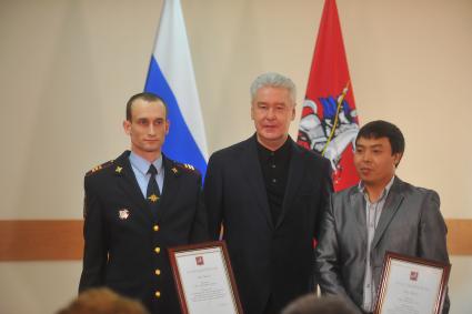 Москва.   Мэр Москвы Сергей Собянин (в центре) награждает полицейского Артема Королюка (слева) и гражданина Киргизии Марата Исаева за спасение женщины 11 февраля 2016 года на станции метро `Красносельская` в ОВД `Южное Медведково`.