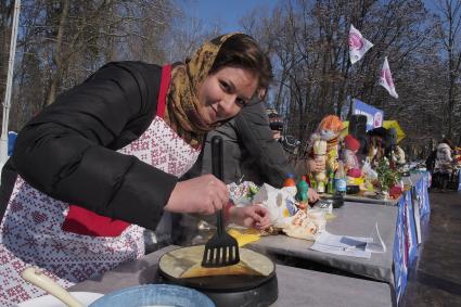 Тула.  Девушка печет блины во время праздника Широкой Масленицы.