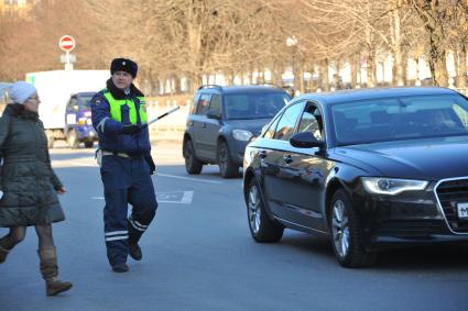 Москва.Сотрудник ДПС помогает женщине перейти улицу.