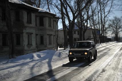 Карабаш.  Машина на улице города на фоне брошенных домов.