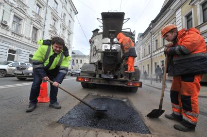 Москва.  Корреспондент `Комсомольской правды` Олег Адамович (слева) во время выполнения работ по ямочному ремонту дорог  на улице Николоямская.