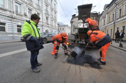 Москва.  Корреспондент `Комсомольской правды` Олег Адамович (слева)  во время выполнения работ по ямочному ремонту дорог  на улице Николоямская.