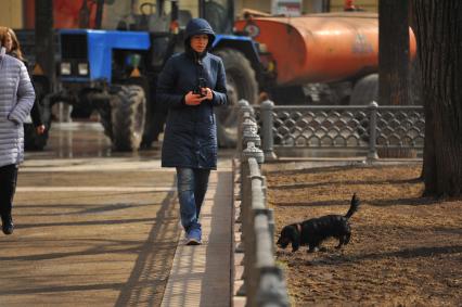 Москва.  Девушка выгуливает собаку на Патриарших прудах.