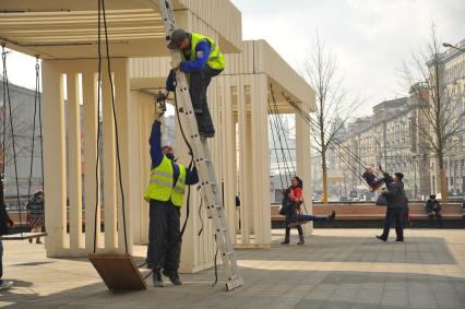 Москва. Рабочие ремонтируют качели на Триумфальной площади.