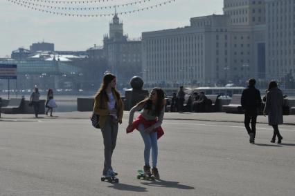 Москва.  Девушки катаются на скейтбордах на Пушкинской набережной Парка Горького.