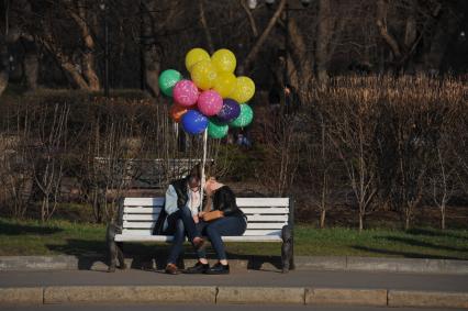 Москва. Влюбленная парана скамейке в парке.