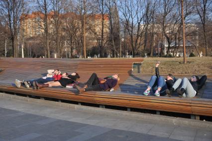 Москва.  Молодежь отдыхает и расслабляется на скамейках парка.