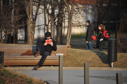 Москва. Мужчина читает книгу на скамейке в парке.