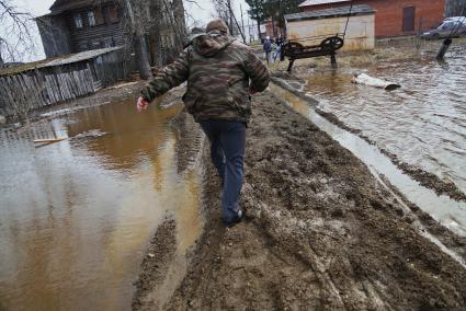 Свердловская область, деревня Махнево. Участковый полицейский идет по подтопленой дорожке во время разлива реки Тагил.