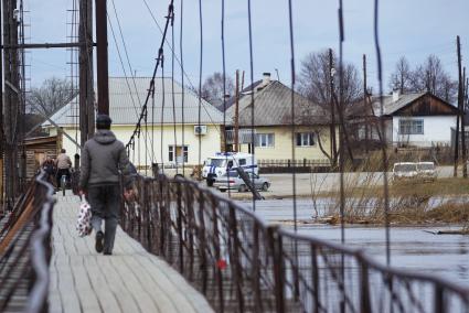 Свердловская область, деревня Махнево. Мужчина с ребенком на велосипеде у подвесного моста во время разлива реки Тагил.