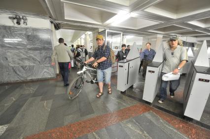 Москва. Корреспондент `Комсомольской правды` Олег Адамович проходит через турникет с велосипедом в метро.