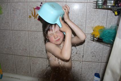 Нижний Новгород.   Ребенок обливается водой из ковша в ванной.