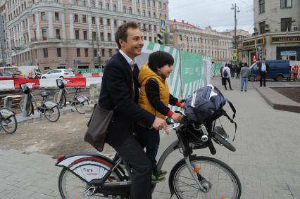 Москва. Мужчина с ребенком едут на велосипеде на Тверской улице.