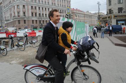 Москва.  Мужчина с ребенком едут на велосипеде на  Тверской улице.