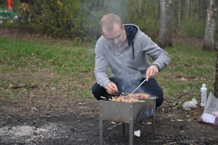 Москва.   Мужчина готовит шашлыки на природе.