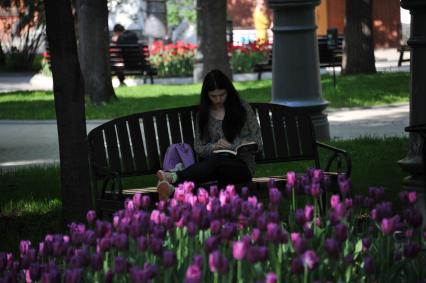 Москва.    Девушка читает книгу в саду `Эрмитаж`.