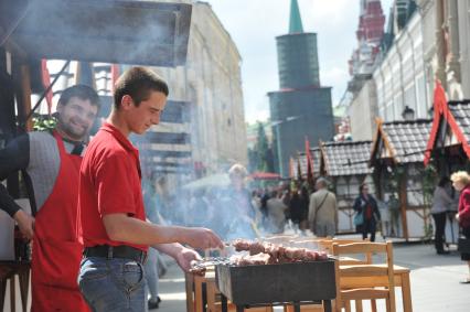 Москва. Мужчина жарит шашлык во время ярмарки  на Никольской улице.