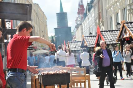 Москва. Мужчина жарит шашлык во время ярмарки  на Никольской улице.