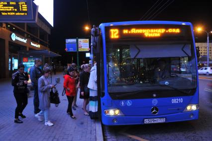 Москва. Пассажиры садятся в автобус на улице города.