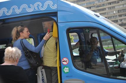 Москва.  Женщина прикладывает проездной билет к валидатору в маршрутном такси компании ООО `Автокарз`.