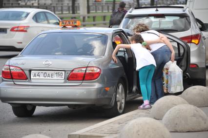 Москва.   Женщина с ребенком садится в такси.